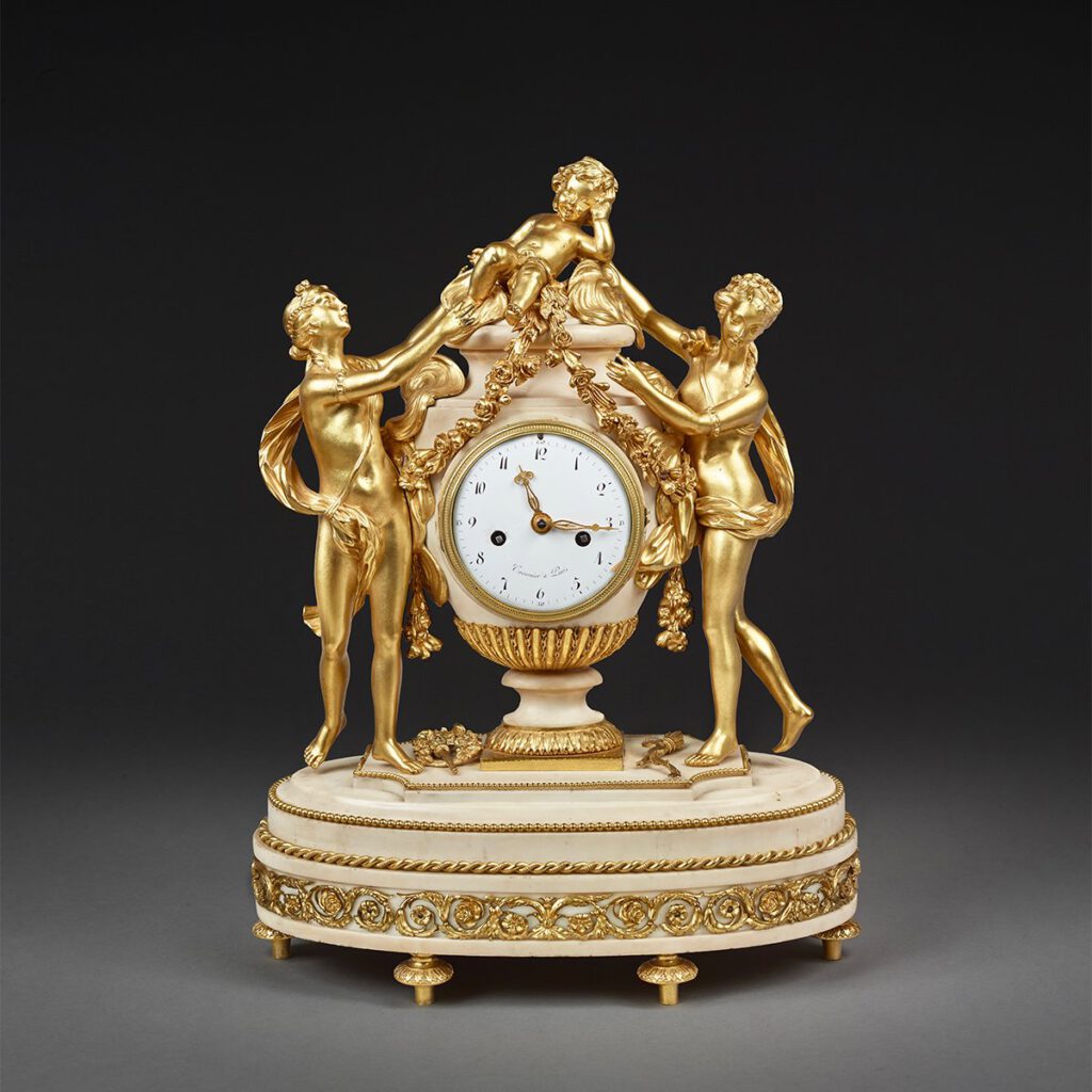 Mantel clock in a vase shape surrounded by two graces  and a putto